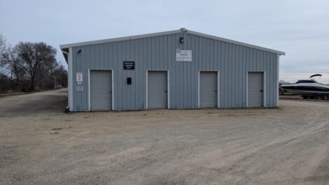 Blue outdoor storage building on a gravel road.
