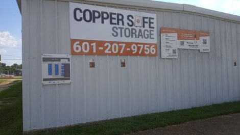 Copper Safe Storage sign on the side of the building with phone numbers in big letters.