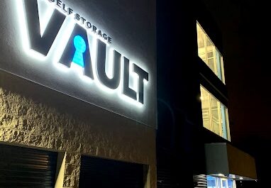 Signage for The Self Storage Vault lit up at night in Bellport, NY.